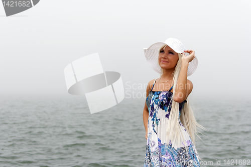 Image of Girl in hat standing in the misty sea