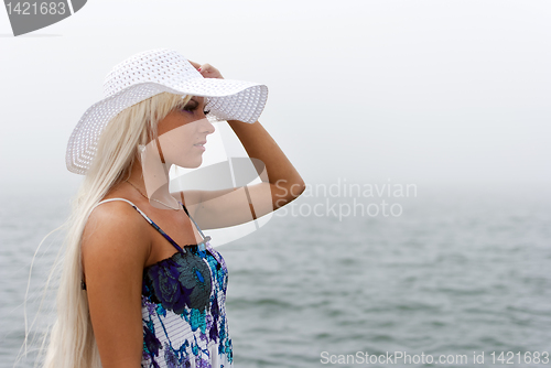Image of Girl in hat standing in the misty sea