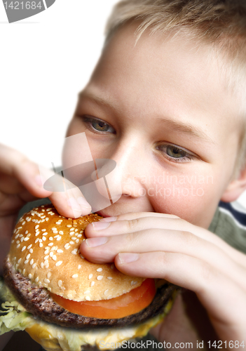 Image of Young boy eating cheeseburger