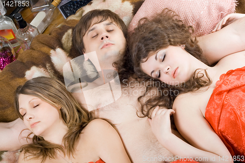 Image of Sleeping young man and two women after a party