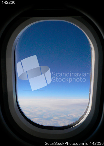 Image of View from aeroplane window onto cloud & blue sky.