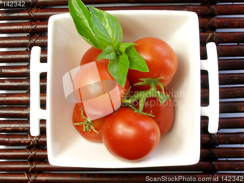 Image of Small tomatoes with a leaf of basil