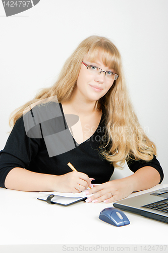 Image of girl with a laptop writes in a notebook