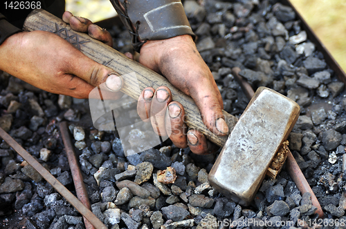 Image of Detail of dirty hands holding hammer - blacksmith