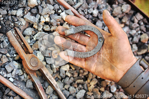 Image of Detail of dirty hand holding horseshoe - blacksmith