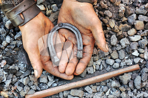 Image of Detail of dirty hands holding horseshoe - blacksmith