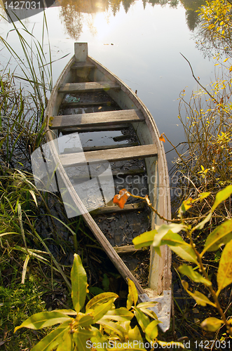Image of Old wooden boat locked at lake. Morning scene.