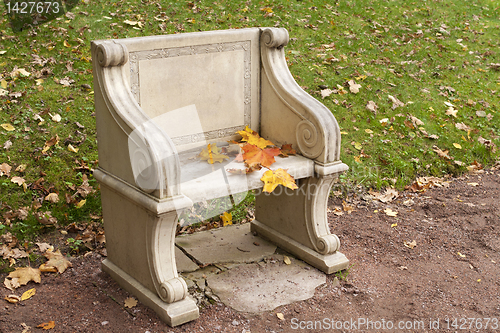 Image of stone park bench with colorful autumn leaves