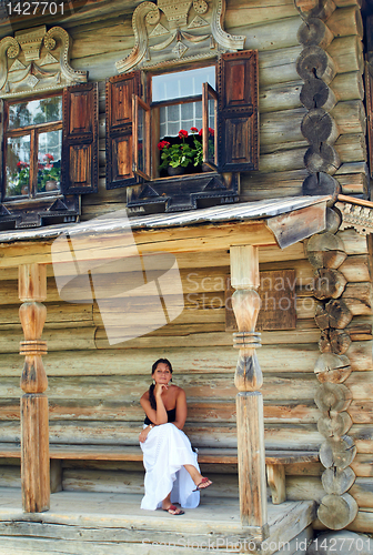 Image of Young woman in front of Old Russian wooden house