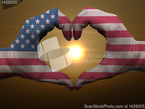 Image of Heart and love gesture by hands colored in american flag during 