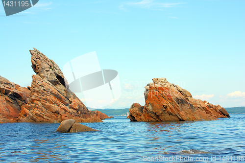 Image of Rocks in the blue sea, illuminated by the sun. Background.