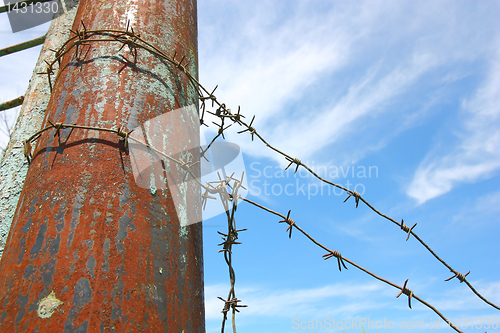 Image of barbed wire on the pole against the blue sky