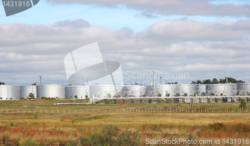Image of white tanks in tank farm with clouds in sky
