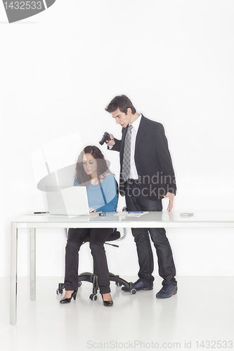 Image of boy in office clothes ponting a gun to a girl 