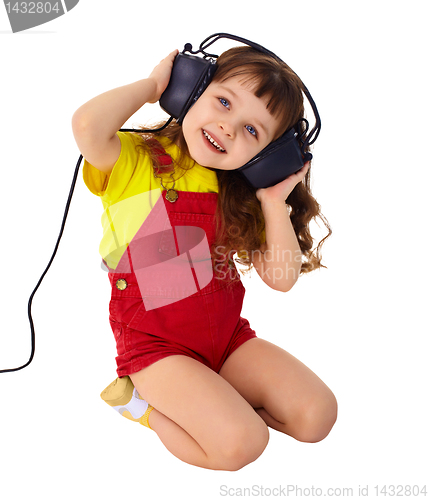 Image of Little girl enjoys music in big headphones