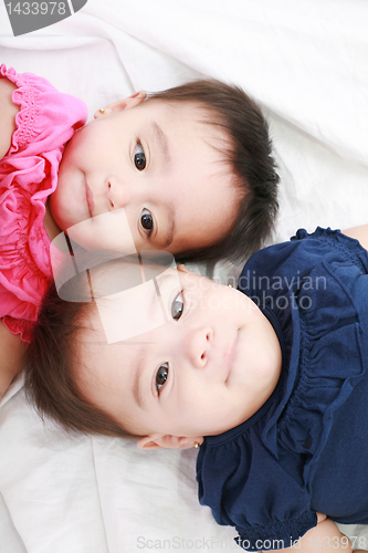 Image of Twin baby sisters lay down in the bed