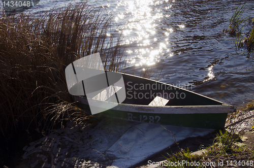 Image of Wooden boat with number on it locked at lake shore