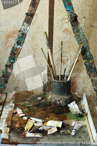 Image of Easel for painting, tubes of oil paint and brushes