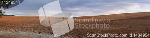 Image of Panorama of orange plowed field in cloudy day before rain