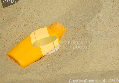 Image of Sunscreen bottle on sand