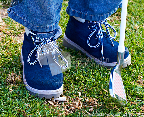 Image of boy shoes and golf club on grass