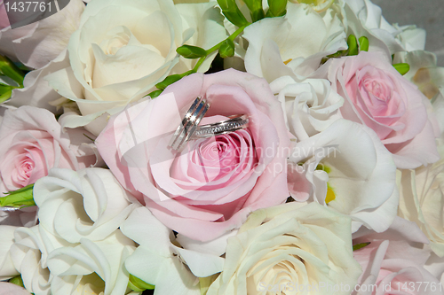 Image of wedding rings on bouquet of bride