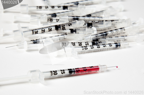 Image of Pile of used syringes with a single filled one