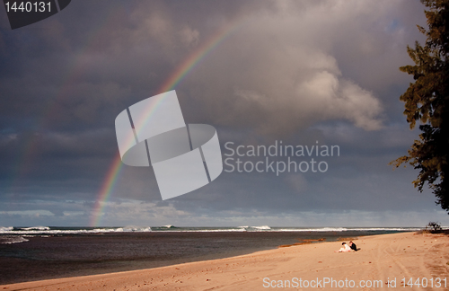 Image of Rainbow over a sandy beach with a couple in distance