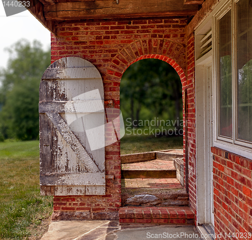 Image of Open wooden door in brick wall to garden