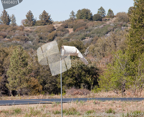 Image of Old white wind sock by paved road