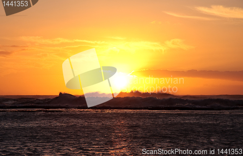 Image of Sun setting over breaking waves off coast of Hawaii