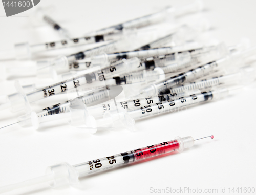 Image of Pile of used syringes with a single one with fluid