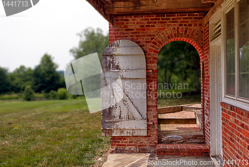 Image of Open wooden door in brick wall to garden