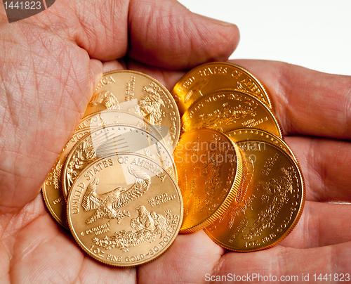 Image of Hand holding stack of gold coins