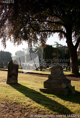 Image of Backlit view of gravestones with church