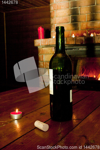 Image of Wine bottle standing on table before fireplace