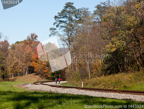 Image of Pair of cyclists ride along railway