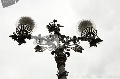 Image of Lamp with metal stand and glass enclosure in park.