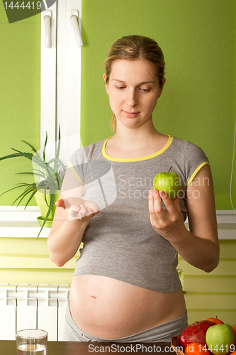 Image of pregnant woman choosing between pills and apple