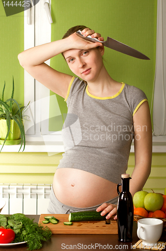 Image of pregnant woman on kitchen with knife