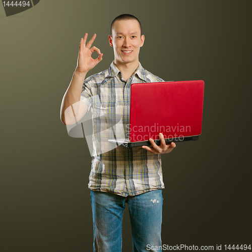 Image of asian male with laptop in his hands shows OK