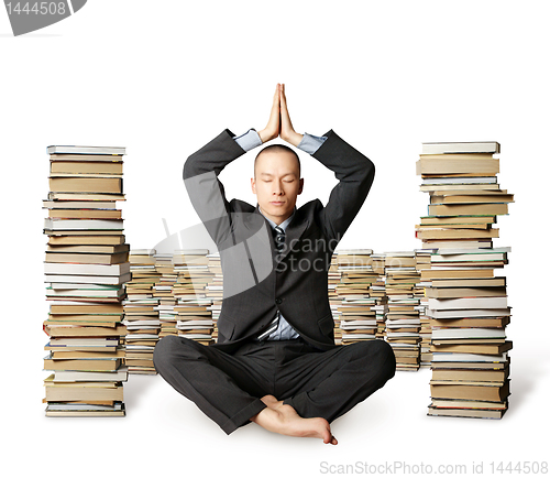 Image of businessman in lotus pose with many books near