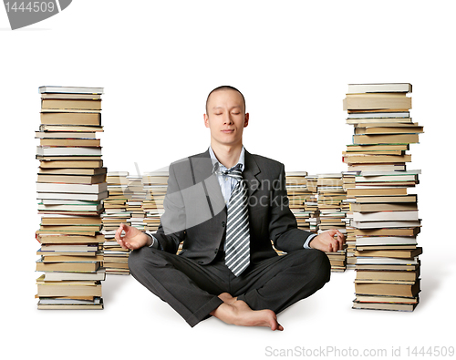 Image of businessman in lotus pose with many books near