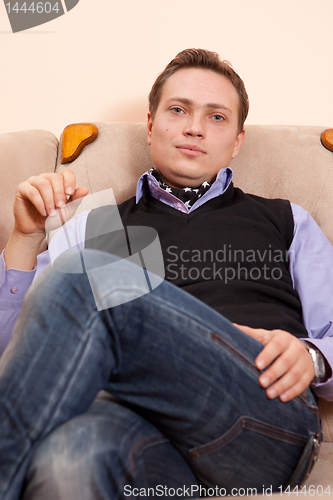 Image of Young man relaxing in armchair