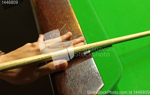 Image of Young man concentrating while aiming at pool ball while playing 