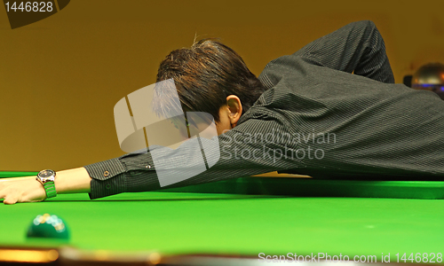 Image of Young man concentrating while aiming at pool ball while playing 