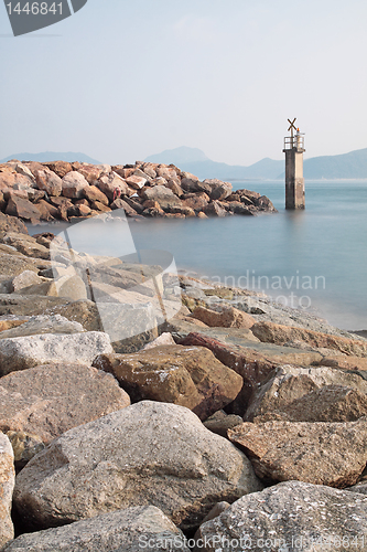 Image of Lighthouse on a Rocky Breakwall: A small lighthouse warns of a r