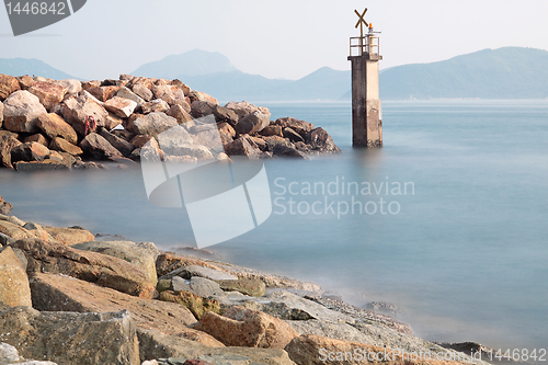 Image of Lighthouse on a Rocky Breakwall: A small lighthouse warns of a r