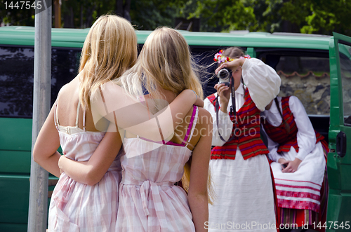 Image of Embracing girls in national costumes posing.