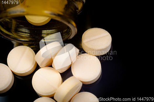 Image of Medical pills out of their bottle on black background